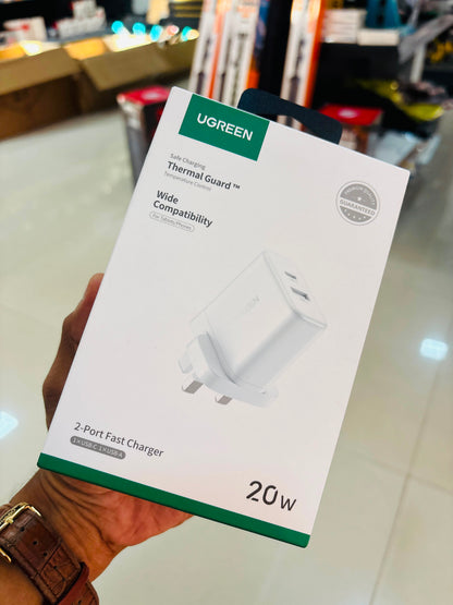 A hand holding a UGREEN 20W thermal guard 2-port fast charger box in a retail store setting.